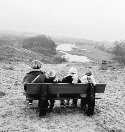Vrouw met kinderen op een bankje in de natuur