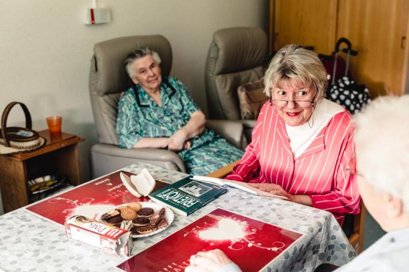 Vrouw leest voor aan bejaarden